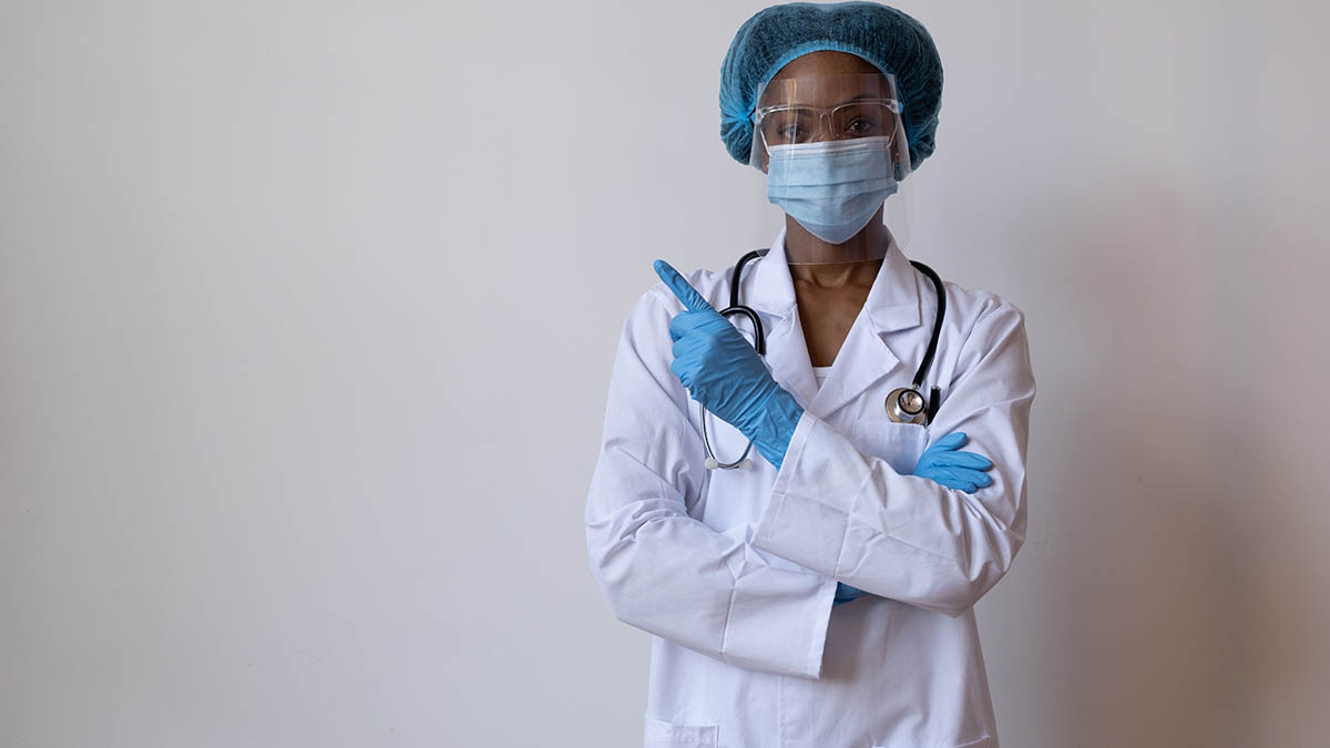 A health worker in protective equipment and face shield