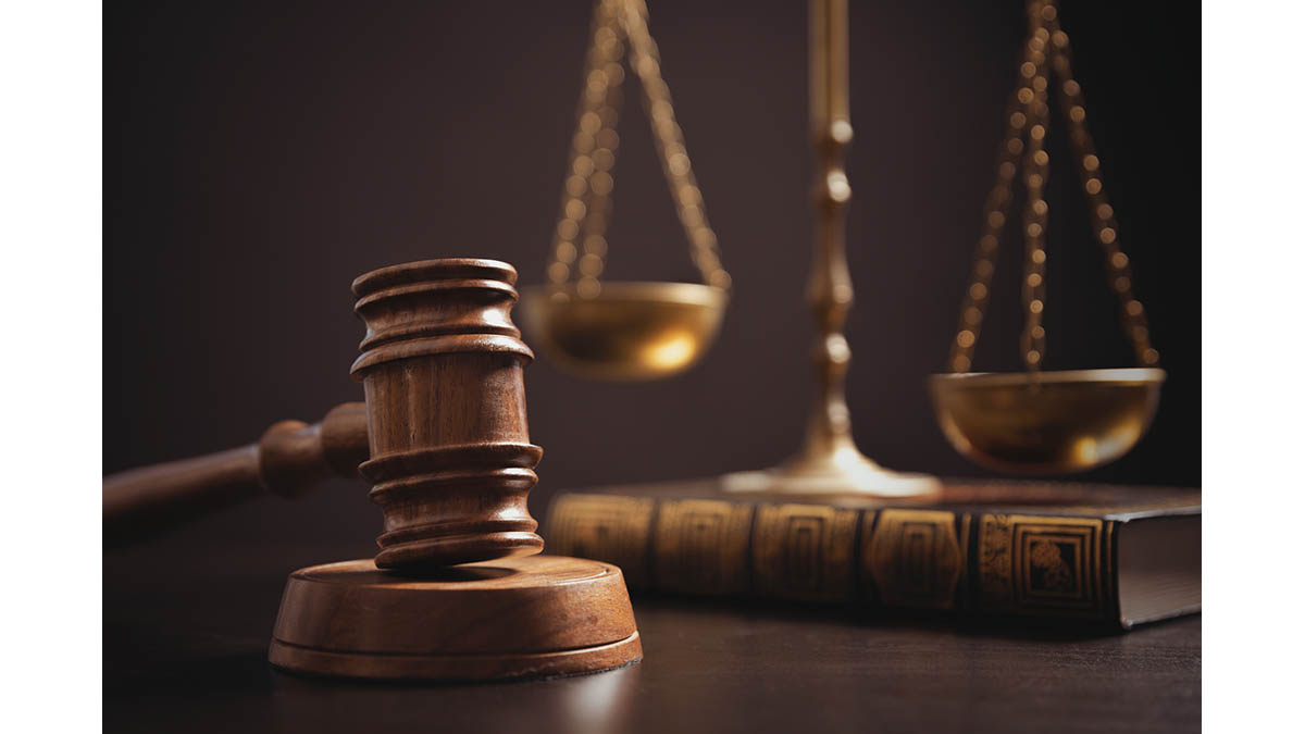 A wooden gavel beside brass scales of justice on a desk