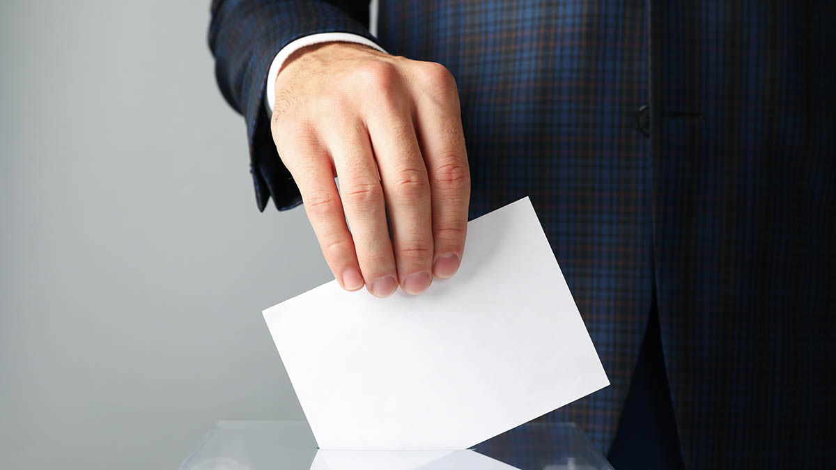 A voter casting a ballot into a box